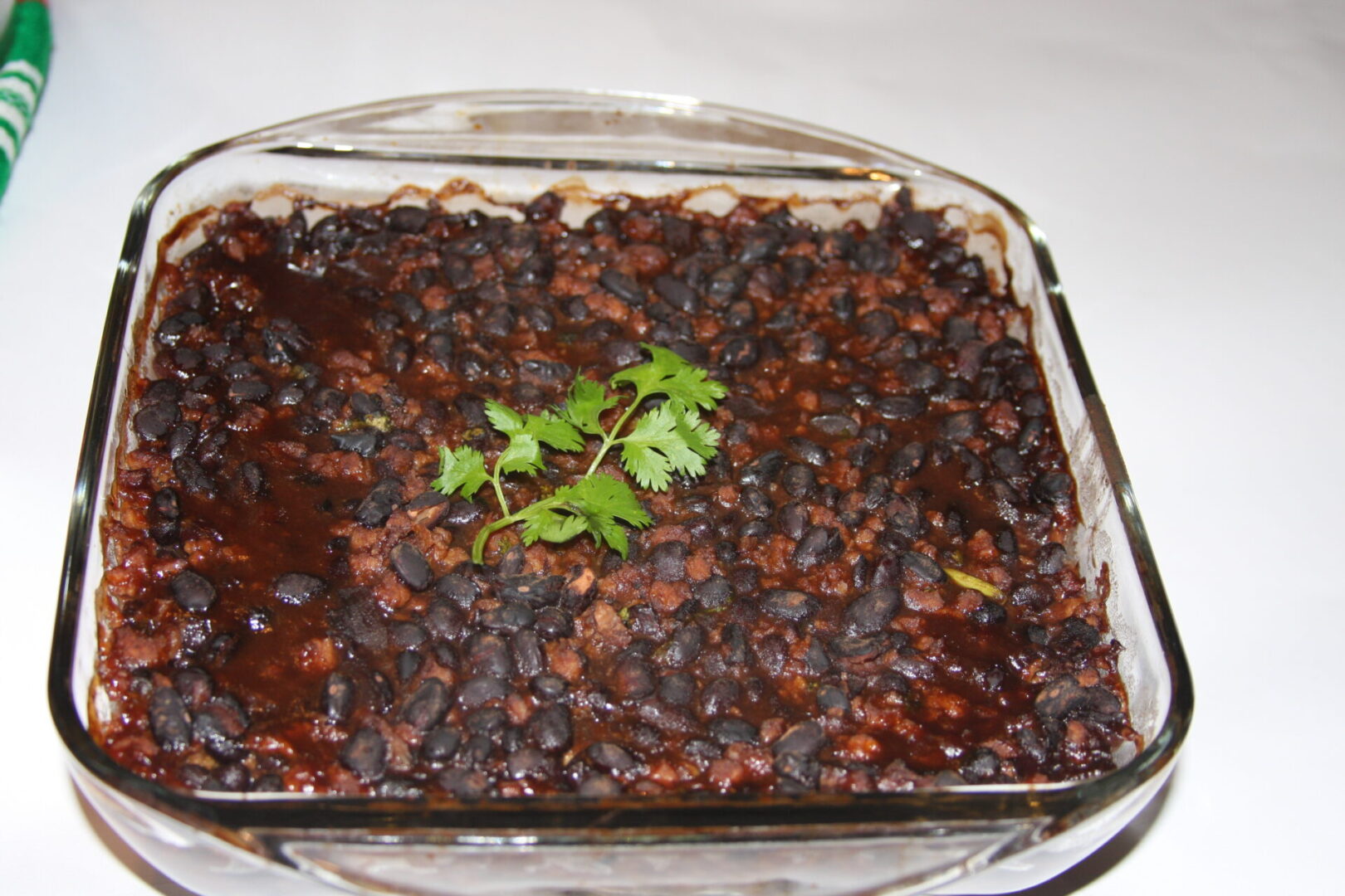 A casserole dish with beans and parsley on top.